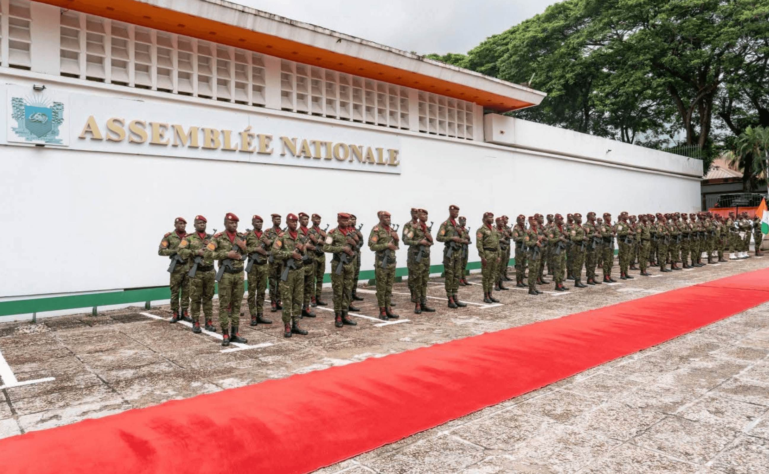 Façade de l'Assemblée Nationale à Abidjan, garde d'honneur alignée le long du tapis rouge.